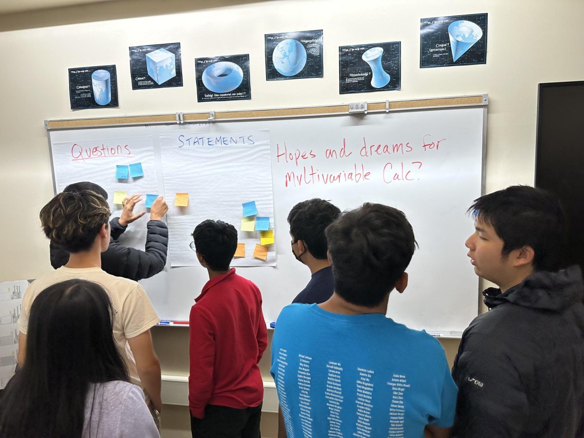 Students add sticky notes about their hopes and dreams for multivariable calculus to posters.