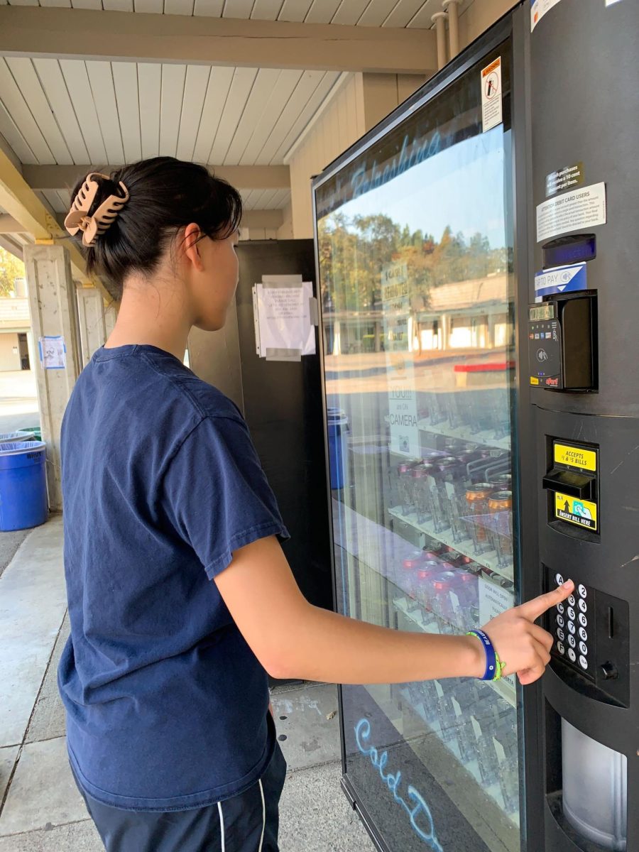 A student purchases snacks from the vending machines located in front of the K-building.