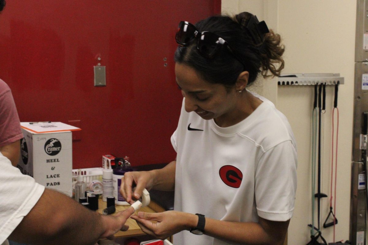 Athletic trainer Gagan Cheema bandages an injured student’s finger.
